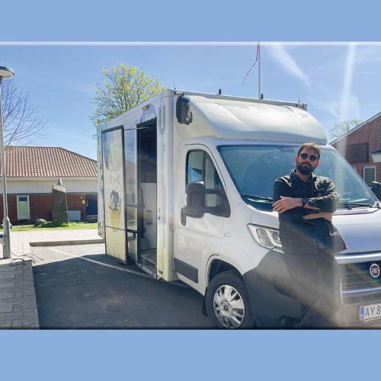 Linus poserer foran bogbussen på en solskinsdag
