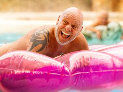 Mand griner i vandet ved en oppustelig, lyserød badebold.