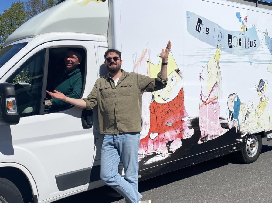 Peter siddende i og Linus stående udenfor Bogbussen